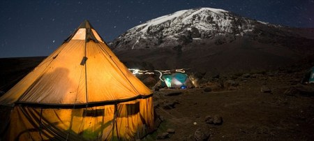Africa Tanzania Kilimanjaro National Park MR Climbing parties tents glow against night sky at Karanga Camp